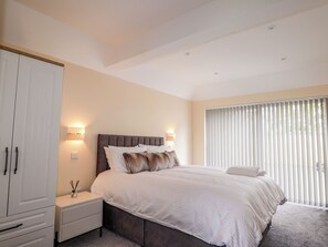 Une chambre à coucher avec un lit, des tables de chevet, une armoire et une fenêtre avec des stores.
