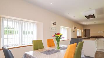 A dining area with a table, chairs, and a vase of flowers.
