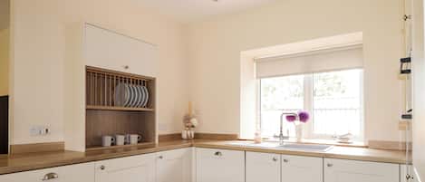 A kitchen with white cabinets, a wooden countertop, a window with a view, and a sink.