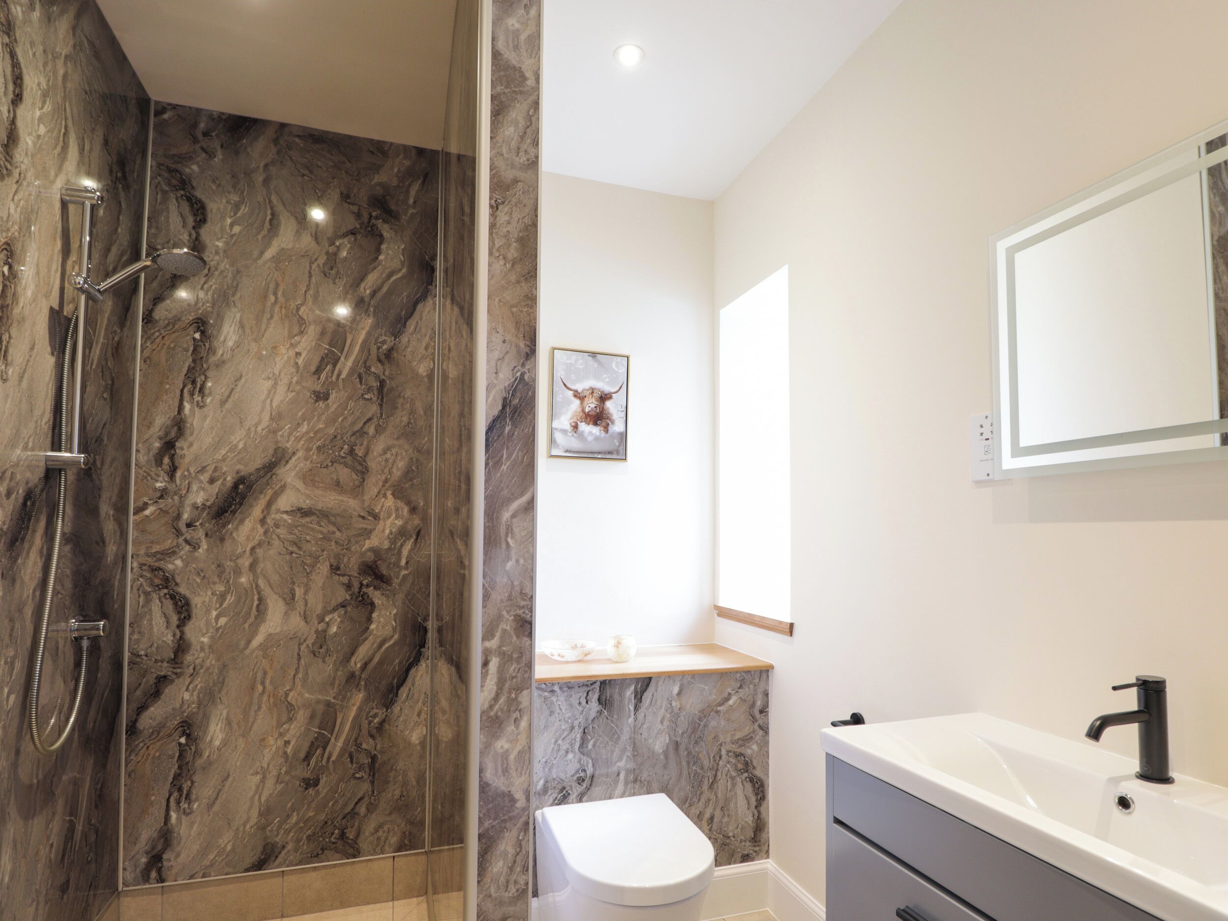 A modern bathroom with a shower, toilet, and sink.