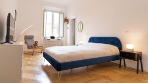 Een slaapkamer met een bed, een bureau, een stoel, een televisie en een spiegel.