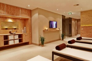 A spa room with wooden paneling, a television, and multiple massage tables. - Sunday Hotel Hannover Superior Room (Hannover)