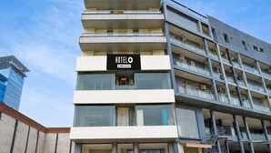 Un hotel de varios pisos con un diseño moderno, que cuenta con un llamativo letrero que dice 'HOTEL' sobre la entrada.