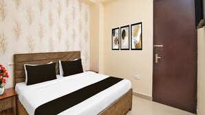 Una habitación de hotel con una cama, una mesita de noche, un florero con flores y una puerta.