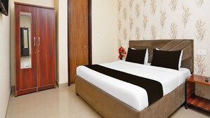 Una habitación de hotel con cama, armario, mesita de noche y papel tapiz floral.