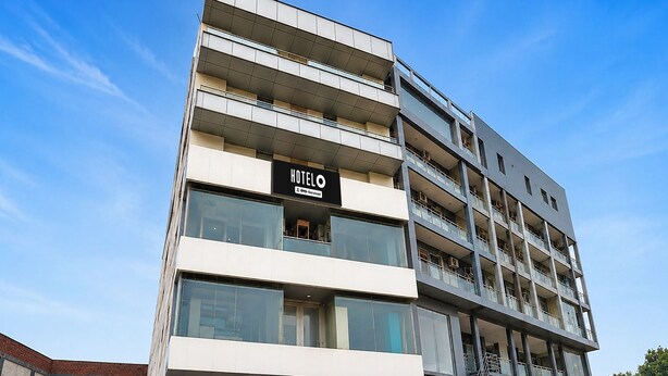 Un hotel de varios pisos con un diseño moderno, que destaca un letrero grande que dice 'HOTEL' en la fachada.