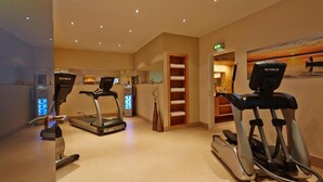 Ein Fitnessraum mit Laufbändern, Crosstrainern und Rudergeräten.