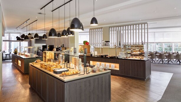 A modern breakfast bar with various food items and a seating area with tables and chairs. - Sunday Hotel Köln Hürth Single Room (Hürth)
