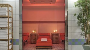 A spa room with a bed, two side tables with candles, a wooden shelf with towels, and a potted plant. - Sunday Hotel Köln Hürth Single Room (Hürth)