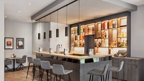A modern bar area with a wooden counter, bar stools, hanging pendant lights, and a well-stocked liquor shelf. - Sunday Hotel Köln Hürth Single Room (Hürth)