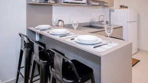 Uma cozinha moderna com uma ilha central, banquetas e um micro-ondas.
