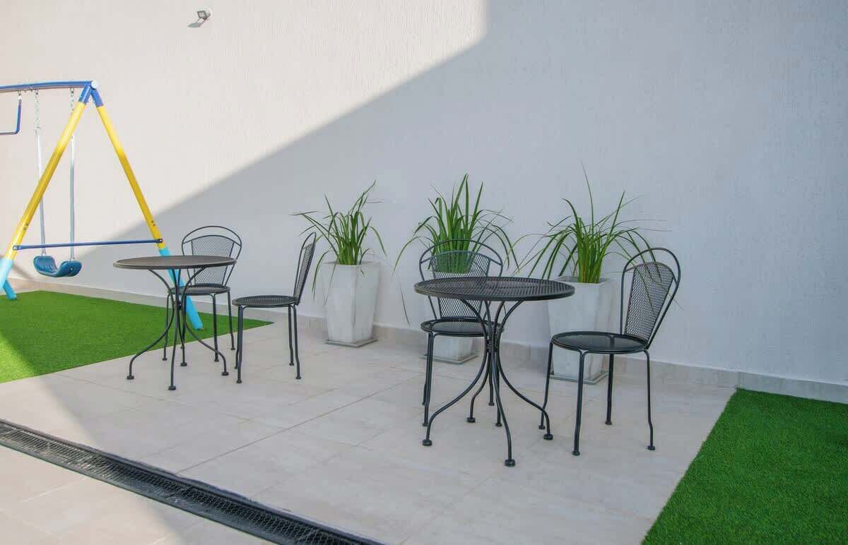Un patio con un columpio, una mesa redonda con sillas y plantas en macetas.