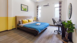 A bedroom with a bed, bedside table, chair, and a potted plant.