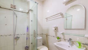 A bathroom with a glass-enclosed shower, a toilet, a sink with a mirror, and a glass shelf.