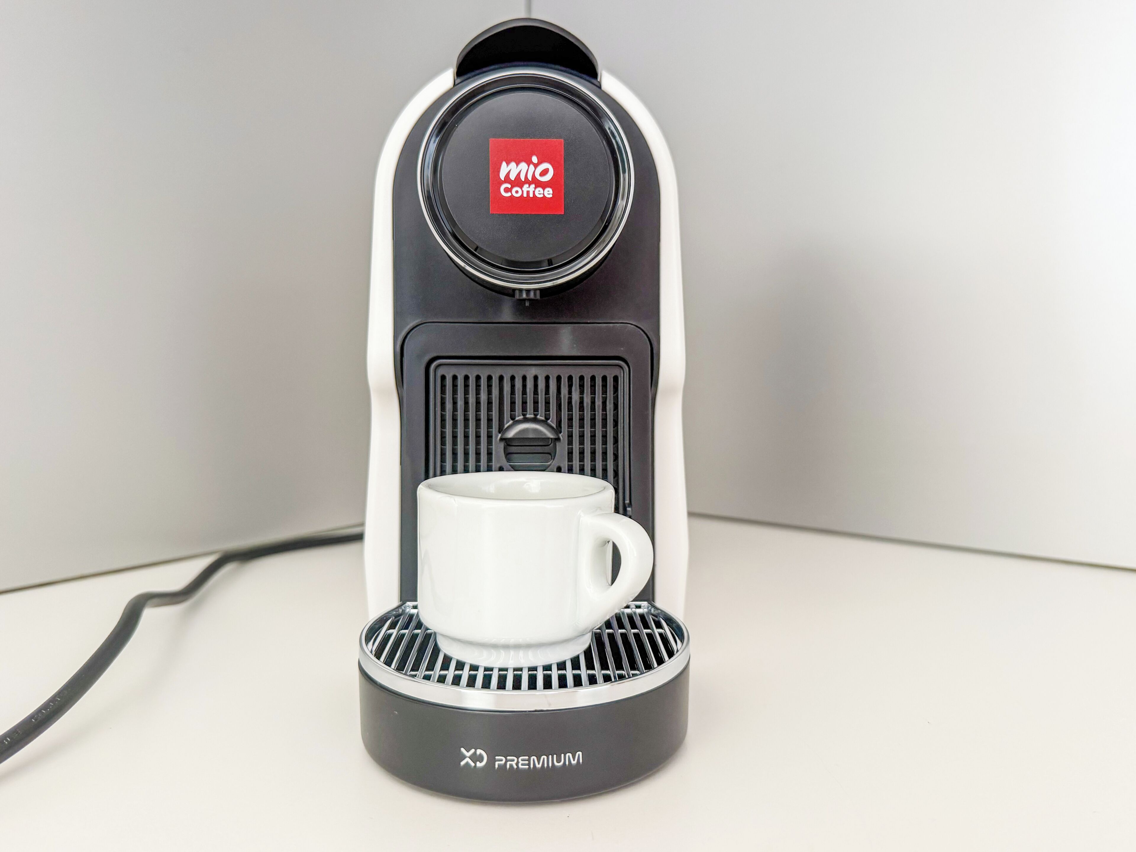 A MIO Coffee espresso machine with a white cup holder and a black base.