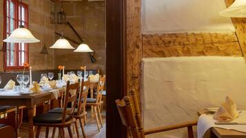 Un espace repas avec des tables et des chaises en bois, ainsi que des luminaires suspendus.