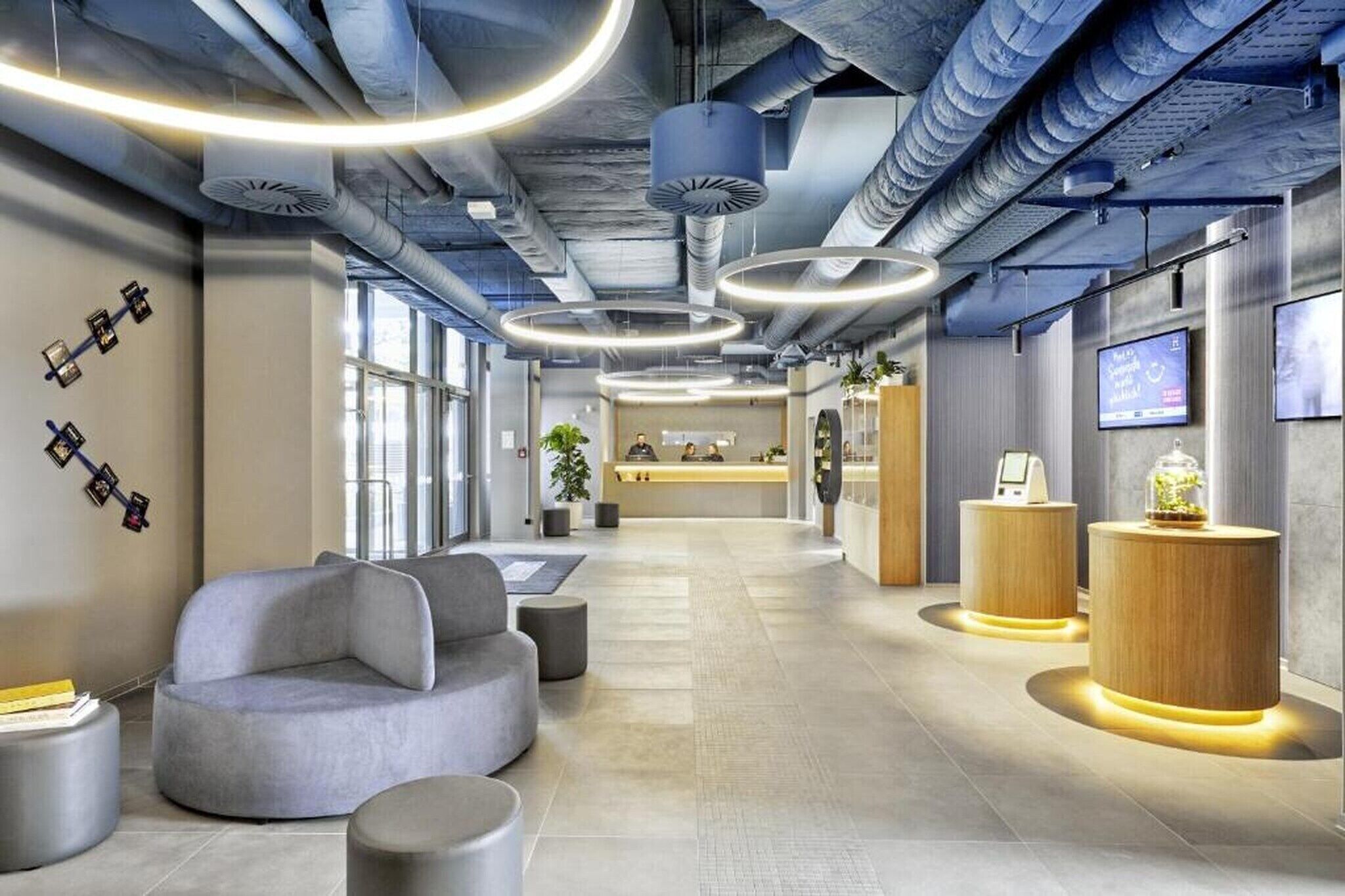 Un vestíbulo moderno con mostrador de recepción, zona de estar e iluminación decorativa.