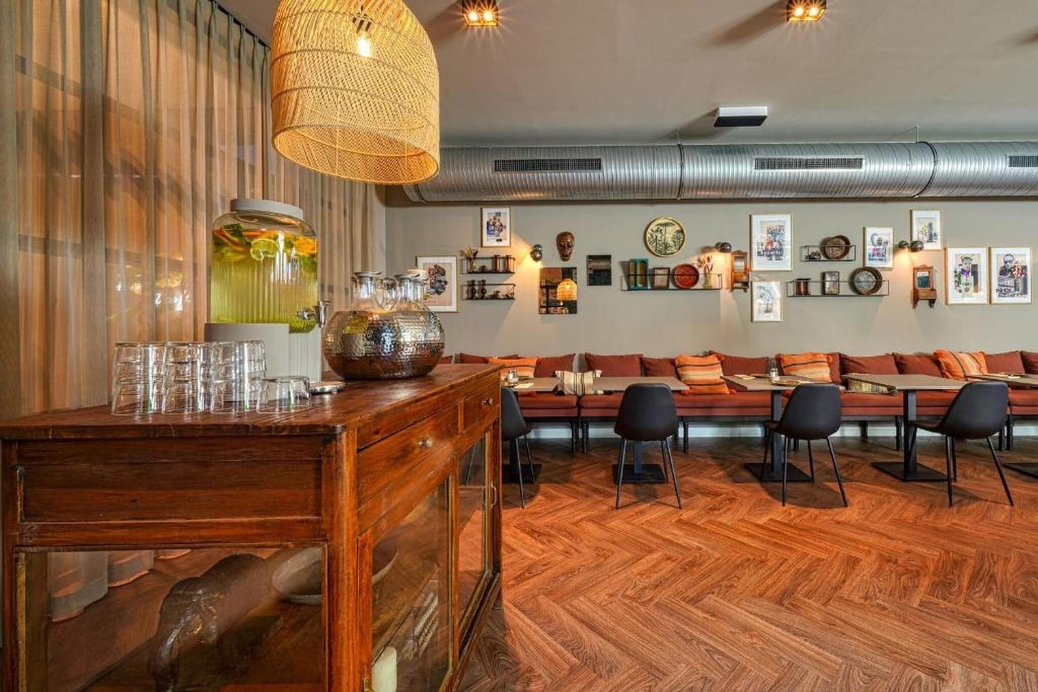 A wooden bar area with a woven light fixture, a large decorative bowl, and a wall adorned with framed pictures and a clock.
