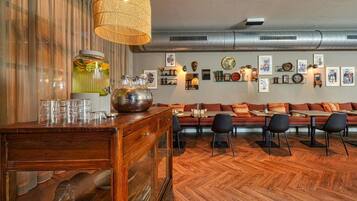 A wooden bar area with a woven light fixture, a large decorative bowl, and a wall adorned with framed pictures and a clock.
