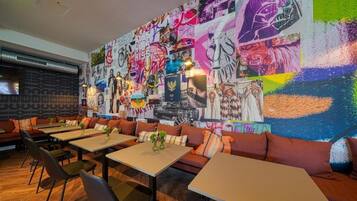 Un restaurante con un mural llamativo, piso de madera y asientos modernos.