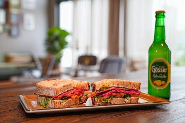 A sandwich on a plate with a bottle of Gösser beer in the background.