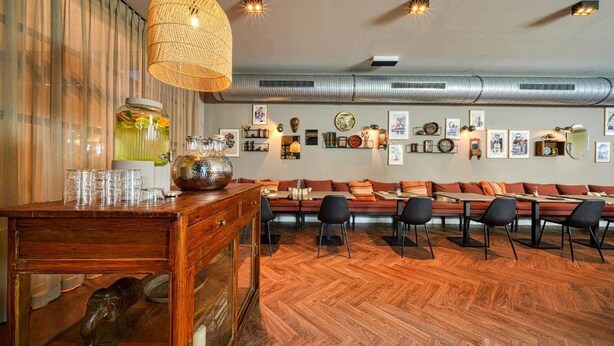 A modern interior with a wooden bar, seating area, and artwork on the walls.