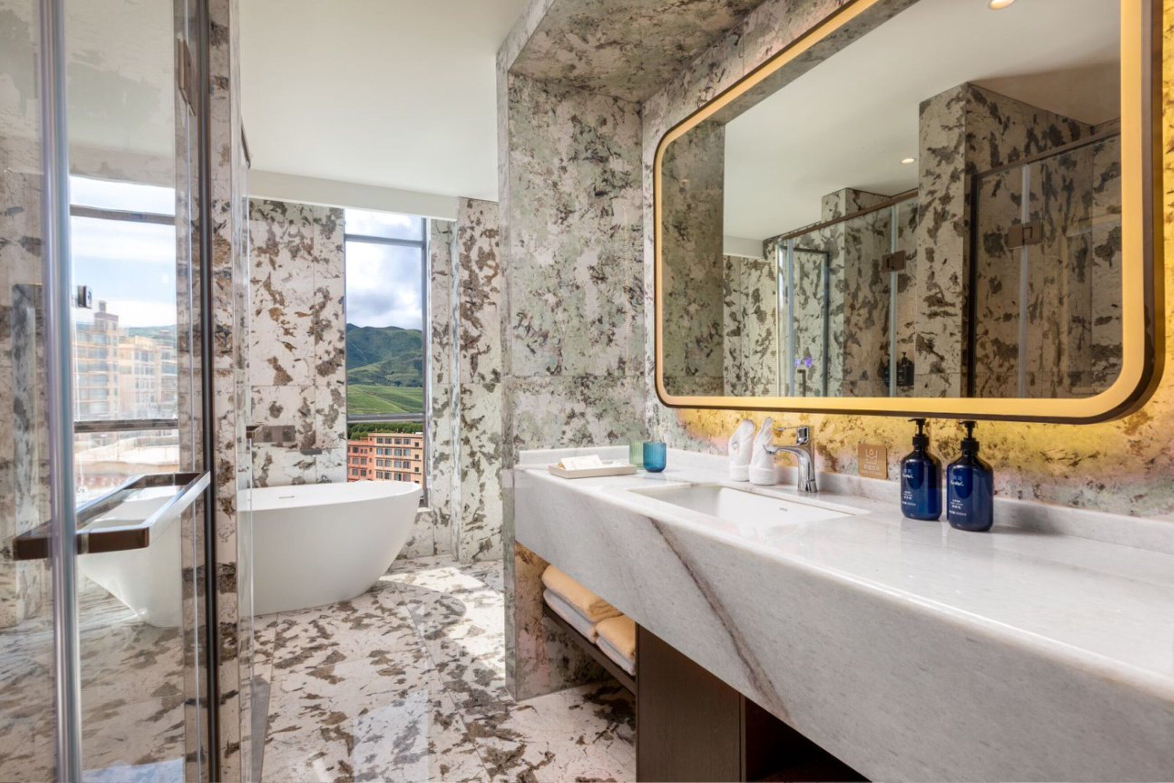 Ein Badezimmer mit einem großen Spiegel, einer Badewanne und einem Waschbecken mit Pflegeprodukten.