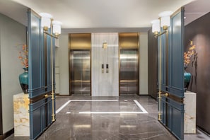 A modern elevator lobby with marble flooring, two elevators, and decorative vases on pedestals. - Holiday Inn Express Ganzi by IHG (Garze)