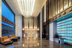 Un vestíbulo moderno con mostrador de recepción, zona de estar y un gran muro iluminado.