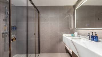 Un baño moderno con cabina de ducha de vidrio, lavamanos de mármol y un espejo grande.
