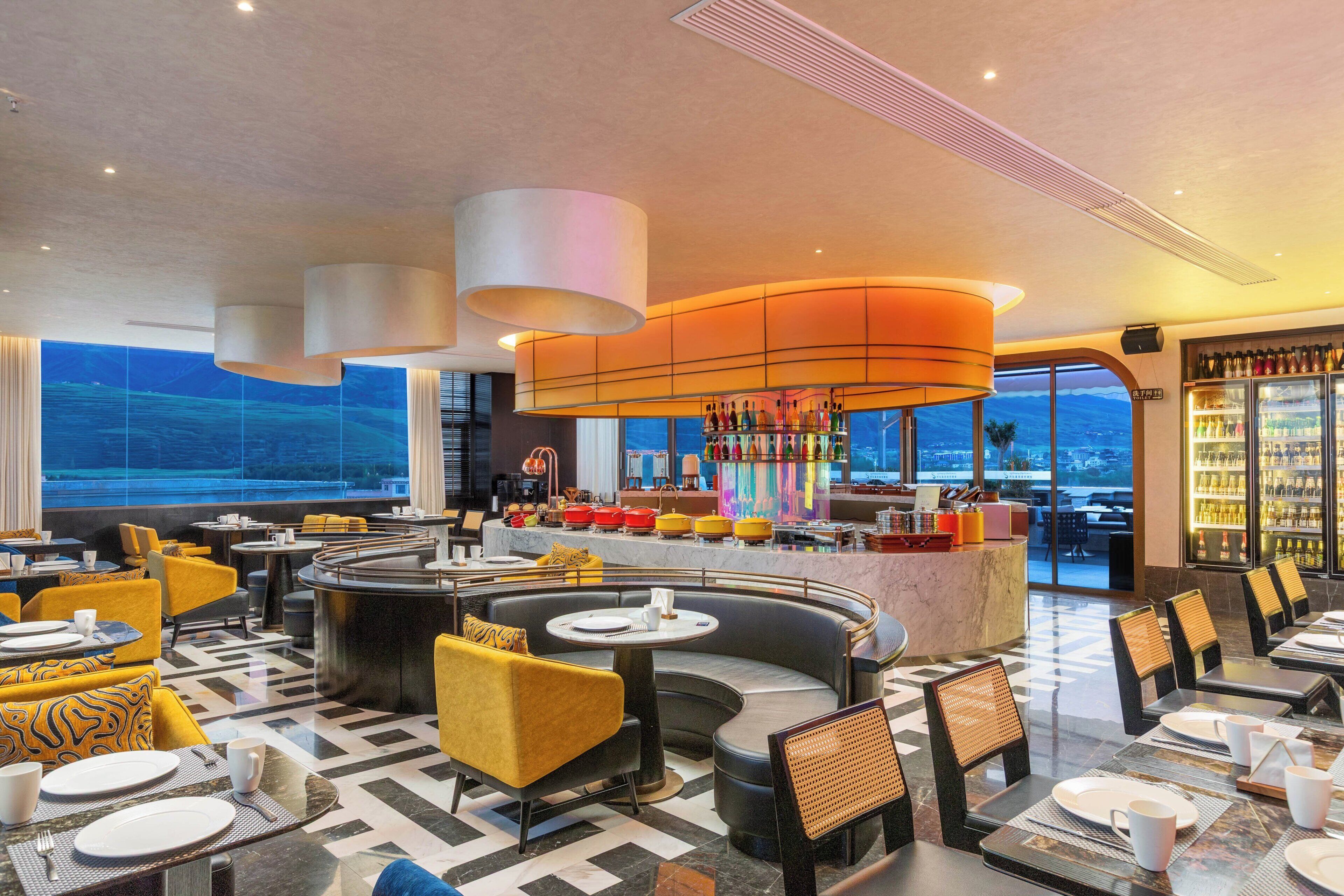 Un moderno vestíbulo de hotel con zona de bar, espacios de descanso y vistas amplias por grandes ventanales.