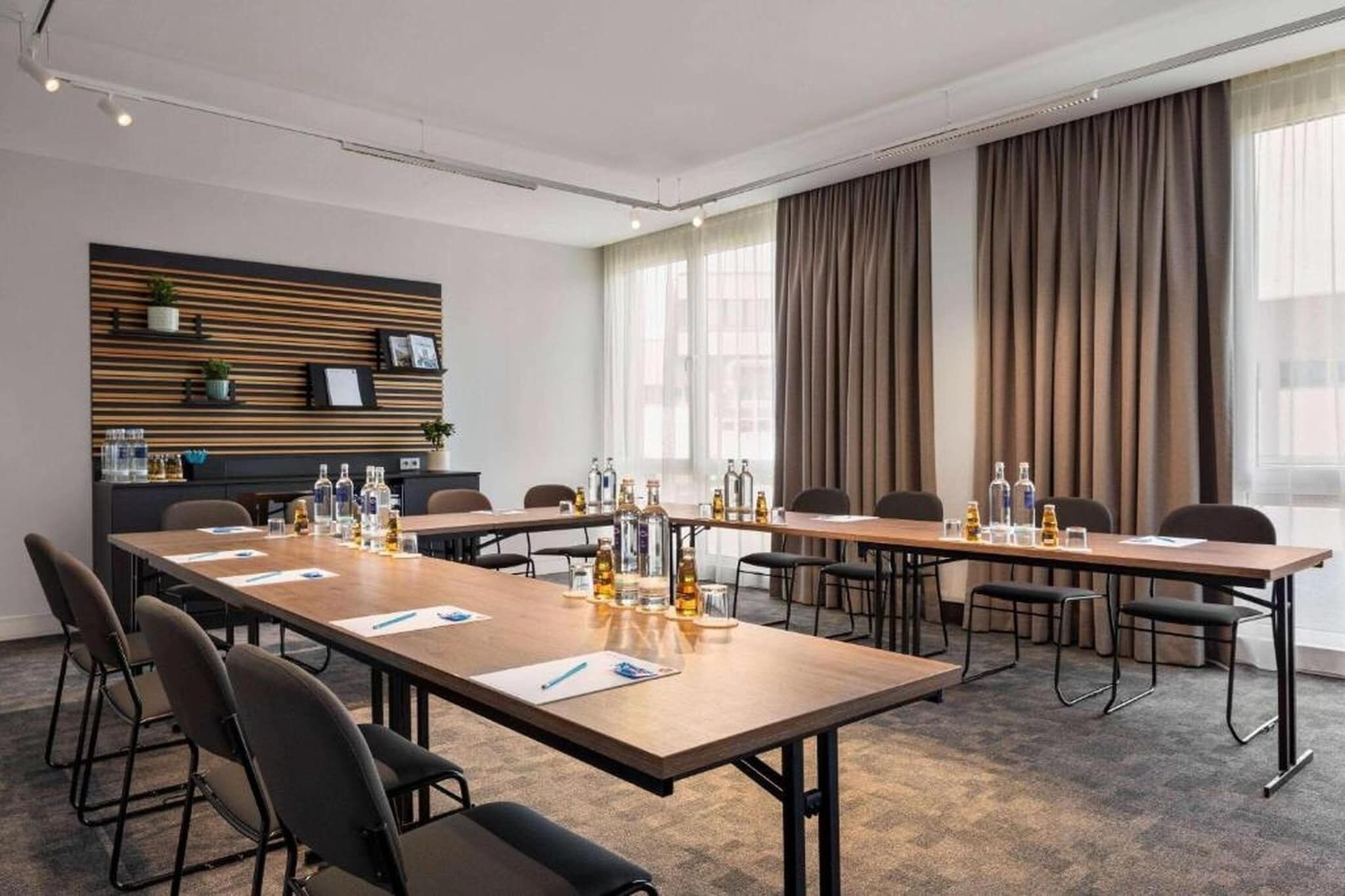 Ein Konferenzraum mit einem langen Tisch, Stühlen und einer an der Wand befestigten Ablage mit Dekorationselementen.