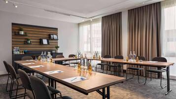 Ein Konferenzraum mit einem langen Tisch, Stühlen und einer an der Wand befestigten Ablage mit Dekorationselementen.