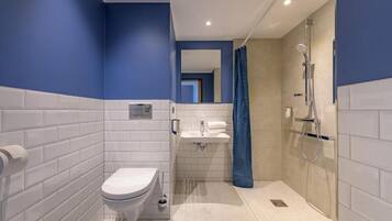 Un baño moderno con azulejos blancos, inodoro, lavabo y ducha.