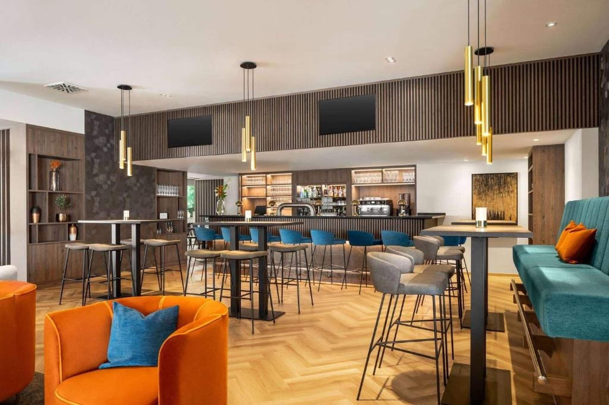 Un espace bar moderne avec des tabourets hauts, un comptoir et un coin salon comprenant un canapé et des fauteuils.