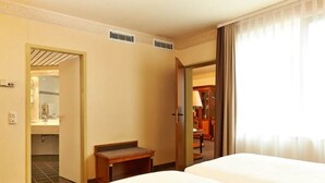 Una habitación de hotel con dos camas, un baño y una zona de estar con una mesa y sillas.