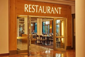 A restaurant with a wooden facade, glass doors, and an interior dining area with tables and chairs.