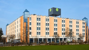 Monikerroksinen hotelli, jossa on moderni muotoilu, huomiota herättävä kyltti katolla ja tasainen kattolinja.