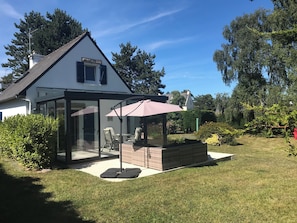 A house with a glass-enclosed patio, a brick fireplace, and a small garden area. - Ti ar Gwez - Cap FREHEL - Beach within walking distance - Sleeps 6  (Fréhel)