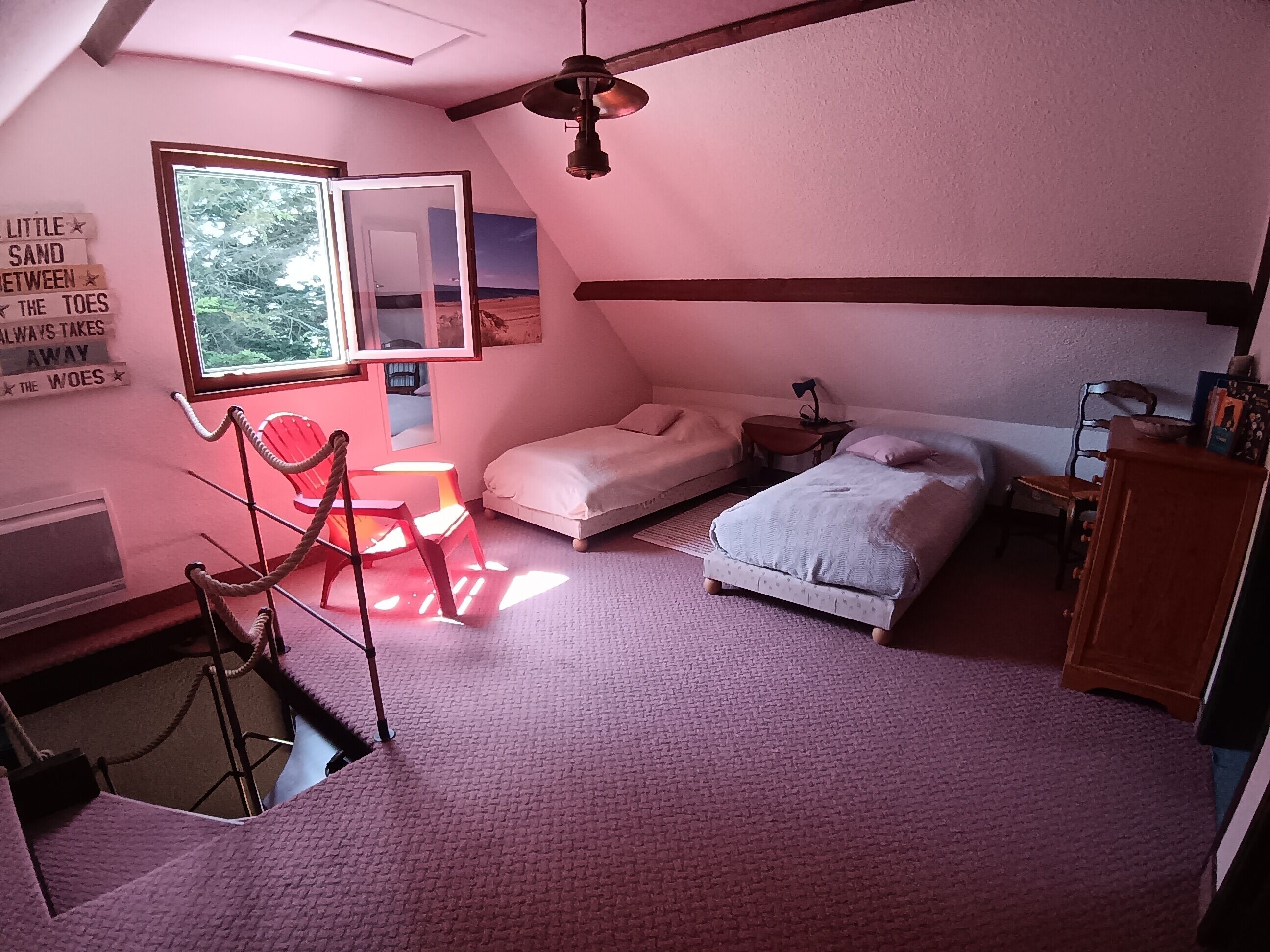 Une chambre avec un plafond en pente, un lit, une chaise, une petite table et un miroir.