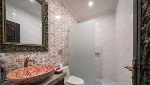 A bathroom with a large oval sink, a toilet, and a shower area.