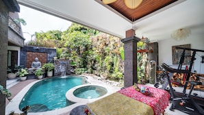 A pool area with a hot tub, exercise equipment, and a variety of plants.