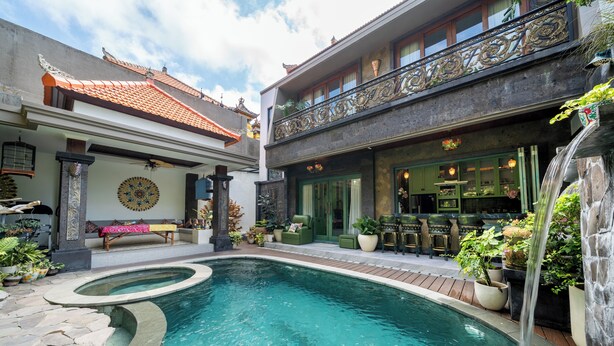 A pool area with a waterfall feature, a covered seating area, and a restaurant with outdoor seating.