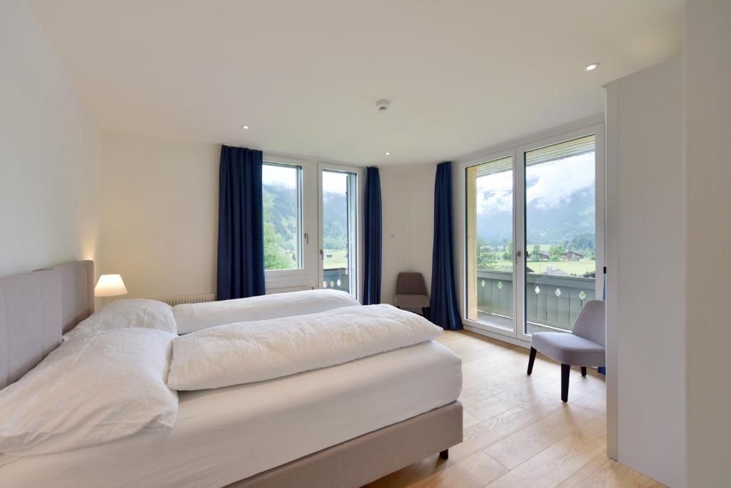 Une chambre d’hôtel avec un grand lit, deux fenêtres, une chaise et un balcon avec vue.