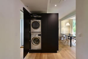 A compact kitchen with a built-in washer and dryer, a dining area with a table and chairs, and a view of the outdoors.