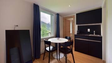 Une cuisine moderne dotée d’une cuisinière intégrée et d’un coin repas avec une table ronde et quatre chaises.