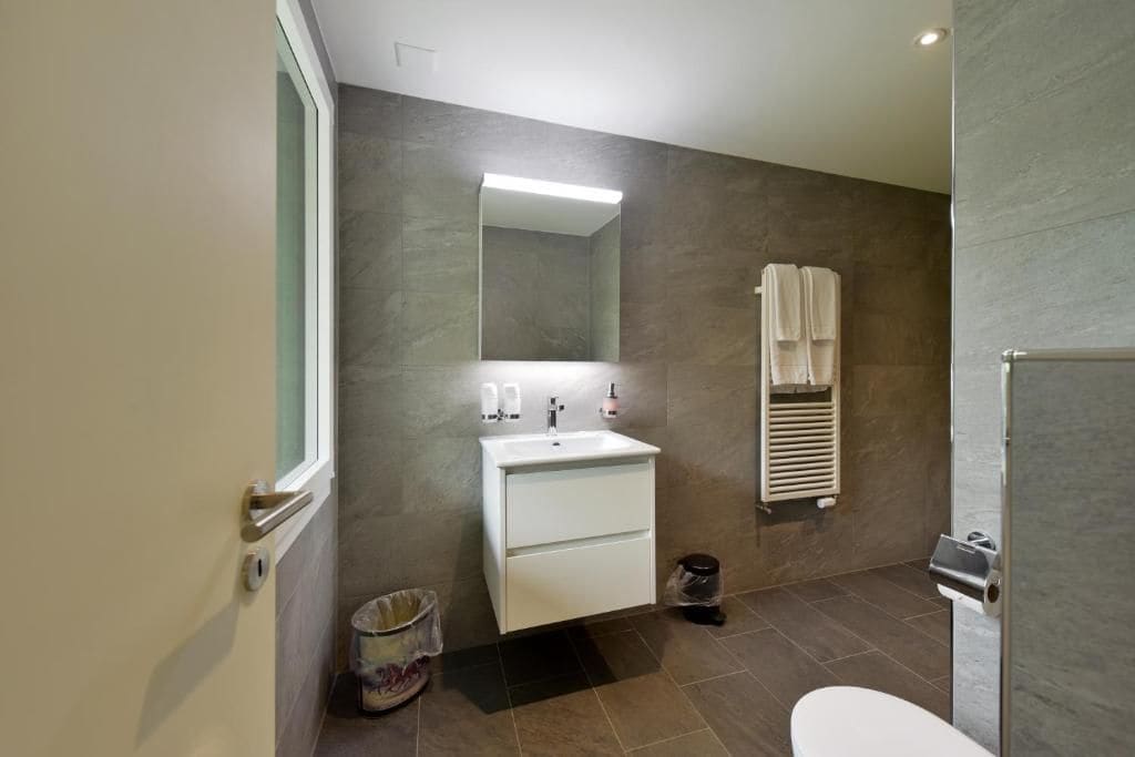 A modern bathroom with a white sink, mirror, and towel rack.