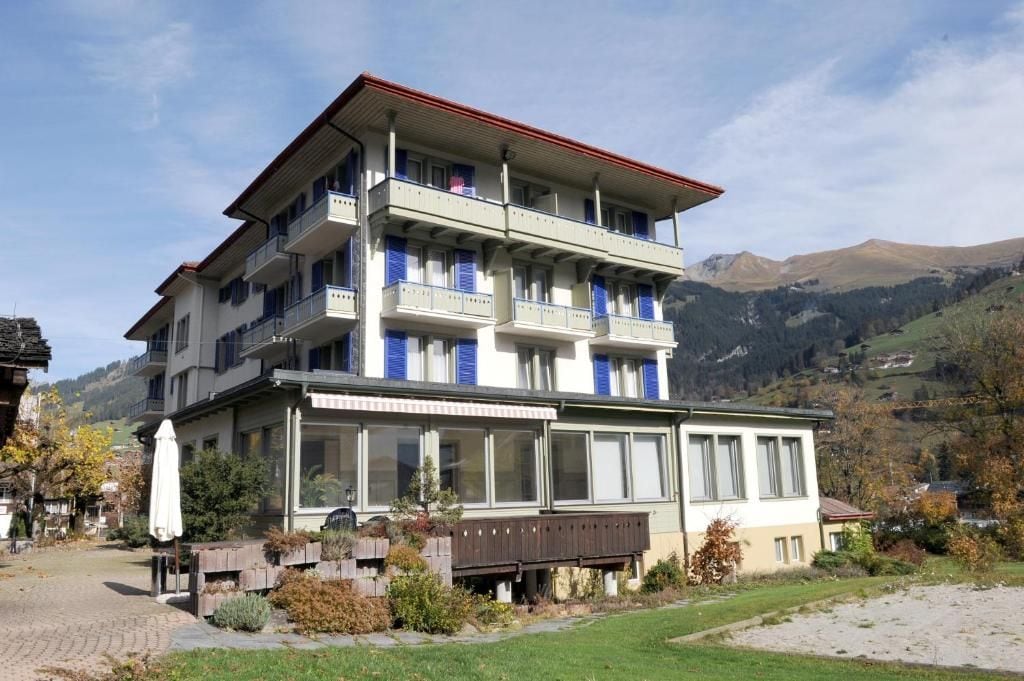 Un hôtel à plusieurs étages, doté de balcons, d’une allée pavée et surplombant un paysage montagneux.