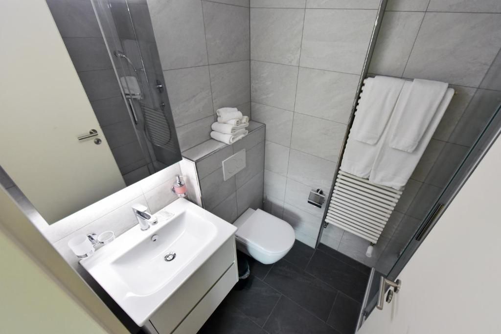 A modern bathroom with a white sink, toilet, and shower.