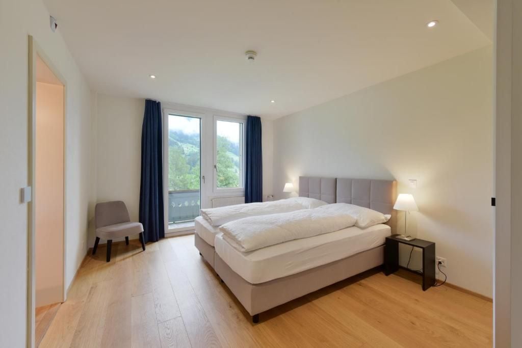 Un dormitorio con una cama doble, una silla, una mesita de noche y vistas por una ventana.